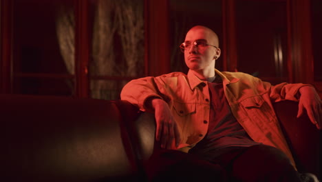 man sitting on a couch in a red lit room