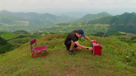 Vídeo-Divertido-De-Un-Hombre-Ajustando-La-Señal-De-Un-Televisor-Antiguo-En-Un-Paisaje-Montañoso