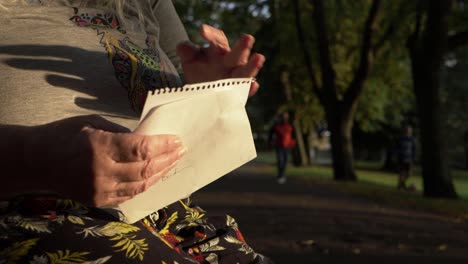 Mature-woman-reacting-to-news-in-a-letter-in-the-park-medium-shot