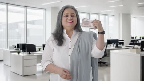happy indian senior businesswoman using money as fan