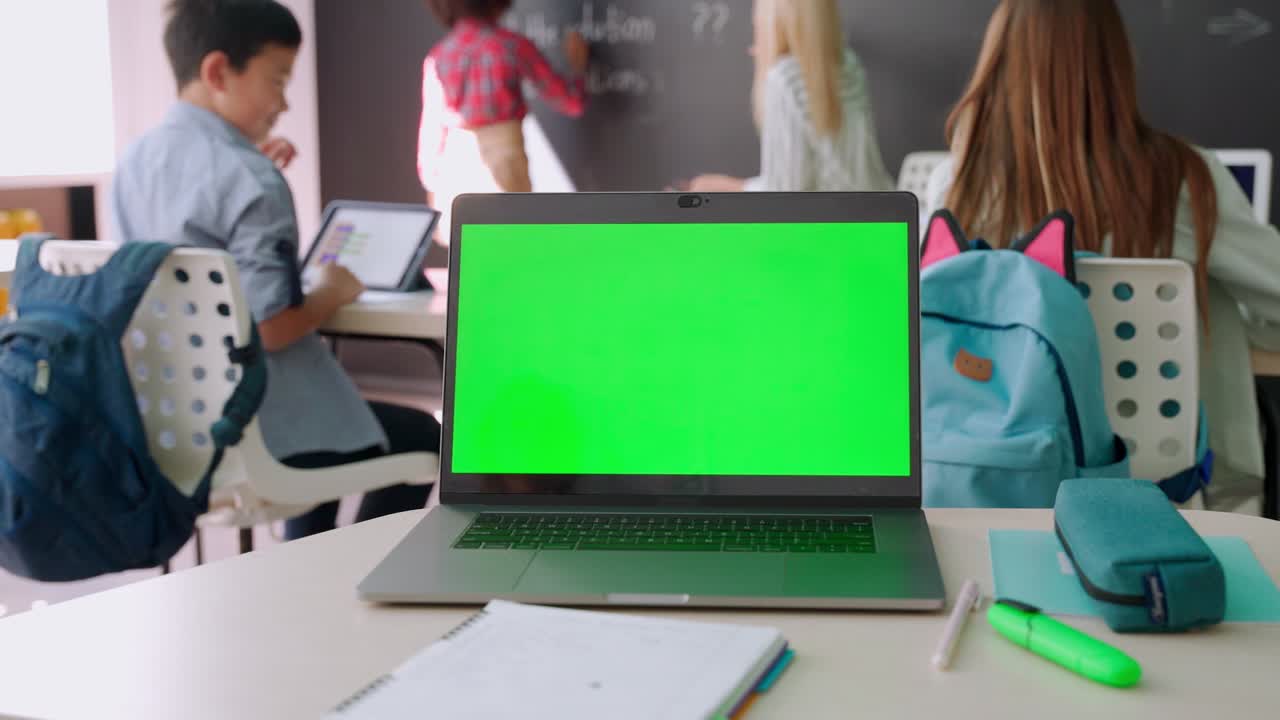 Laptop computer blank empty green mockup screen on school desk in classroom.