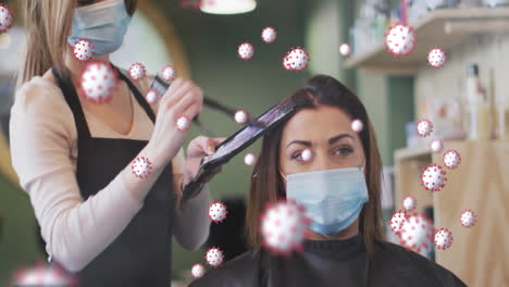 animation of coronavirus cells over caucasian female hairdresser and woman wearing face masks