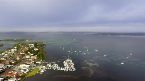 aerial drone shot flying over lake macquarie, australia, approaching a small marina and looking out towards islands and reefs