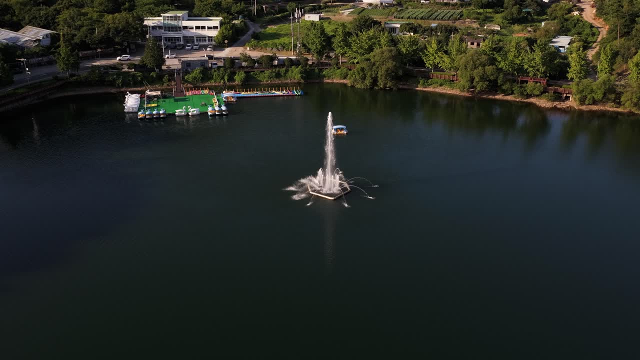 Aerial drone shot circling and descending towards a water fountain on a lake