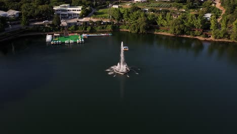 aerial drone shot circling and descending towards a water fountain on a lake