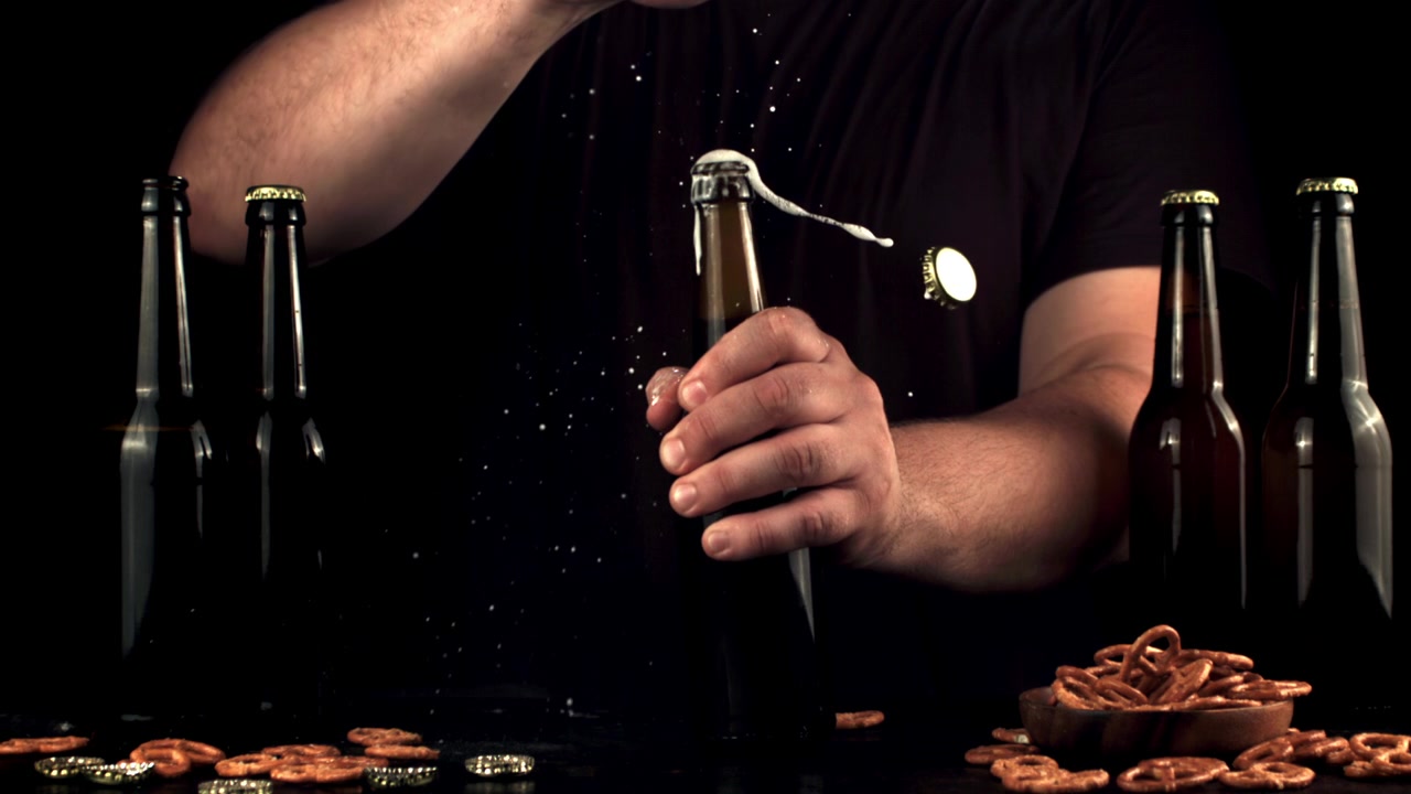 Rallentatore di un uomo che apre una bottiglia di birra con schiuma