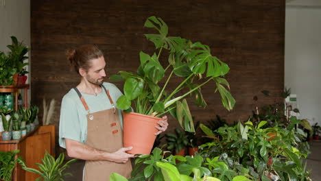 man holding a monstera plant in a plant shop