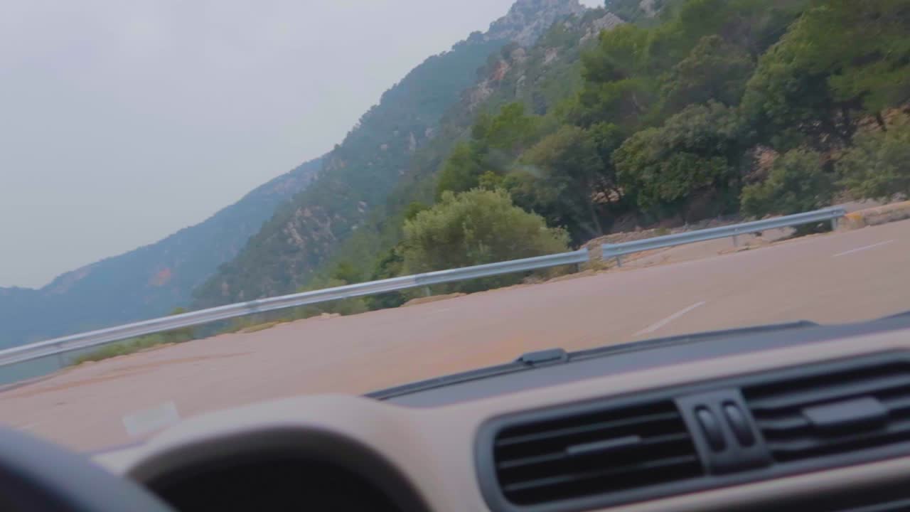 운전자가 언덕이 많은 지역에서 지그재그로 회전하는 동안 자동차 조향 장치와 대시보드를 자세히 볼 수 있습니다.