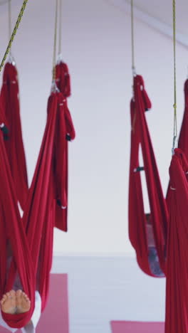 hanging anti-gravity yoga hammocks with sleeping tired women with bare feet relaxing after hard workout