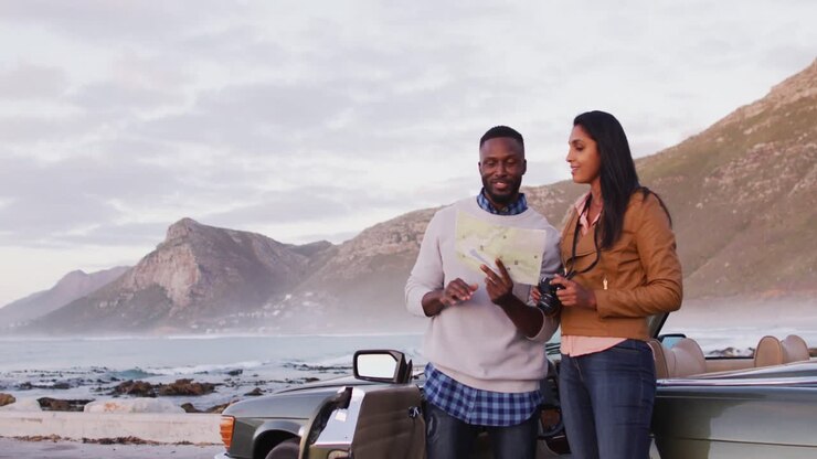 Couple afro-américain utilisant une carte pour s'orienter, debout près de la voiture décapotable sur la route.