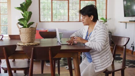 Mujer-Mayor-Asiática-Sosteniendo-Su-Espalda-Con-Dolor-Mientras-Se-Levanta-De-Una-Silla-En-Casa