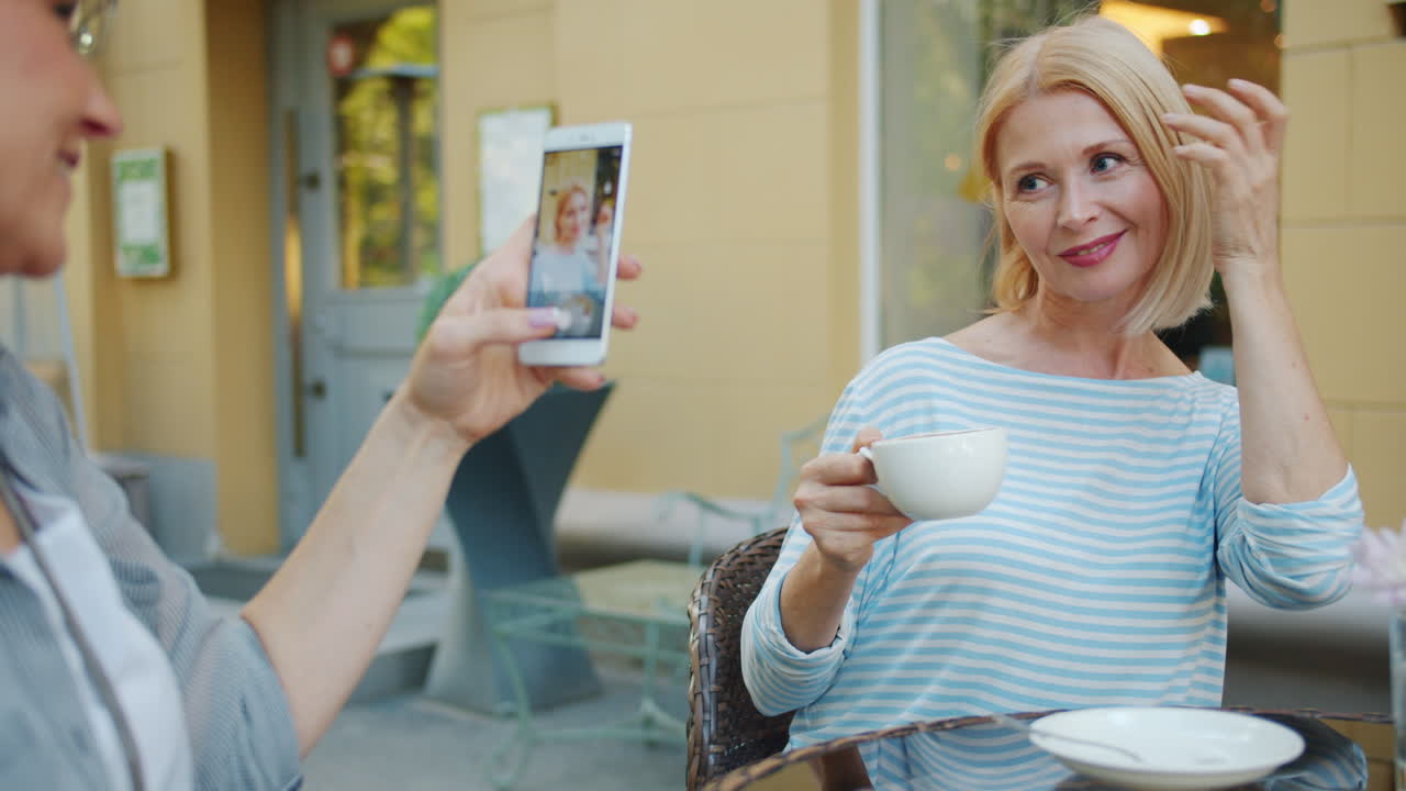 Two women enjoying coffee and taking a selfie outdoors