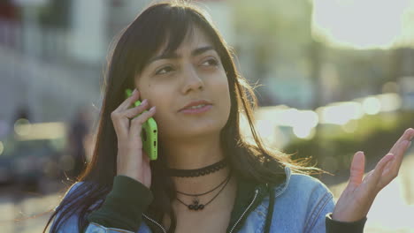una adolescente preocupada hablando con su teléfono inteligente al aire libre.