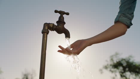 Bäuerin-Wäscht-Sich-Die-Hände-Unter-Leitungswasser-Auf-Einem-Ländlichen-Bauernhof-Mit-Süßwasser,-Das-Aus-Dem-Wasserhahn-Fließt,-Während-Die-Nachmittagssonne-Aufflackert