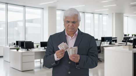 el gerente senior indio tenso contando dinero.