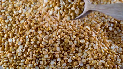 a pile of yellow peas with a wooden spoon on the table. high-protein legumes, beans and lentils for a healthy diet