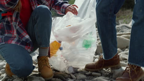 couple collecting bottles into bag . woman and man giving high five for good job