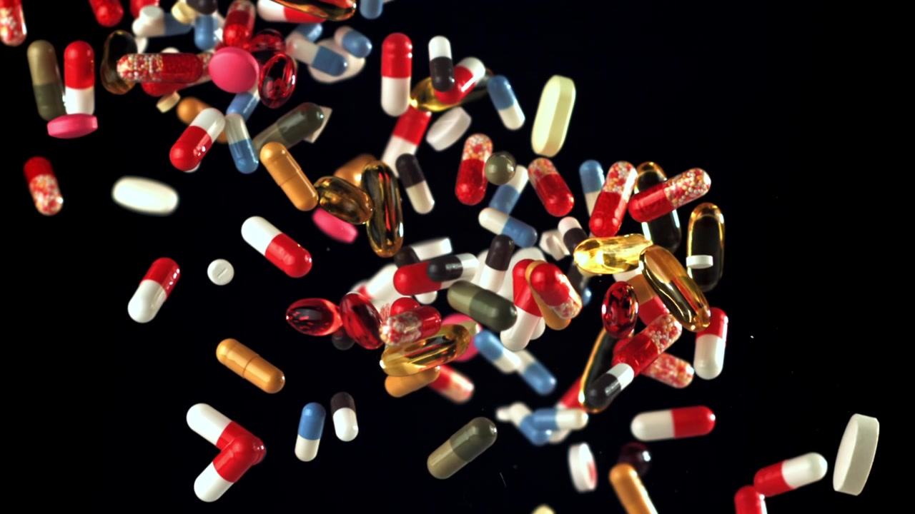 Colorful Pills and Capsules Falling in Slow Motion Against a Black Background