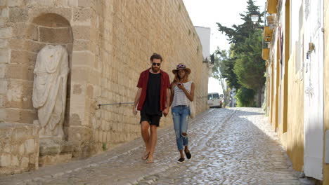 Couple-walking-hand-in-hand-towards-camera-in-Ibiza-street