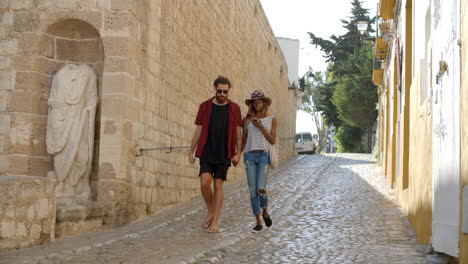 couple walking hand in hand towards camera in ibiza street