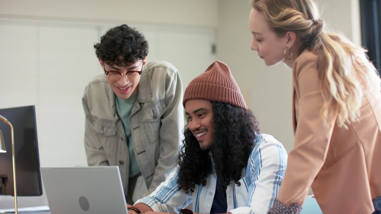 Diverse coworkers collaborating on laptop upon scrolling through document, revising draft in office
