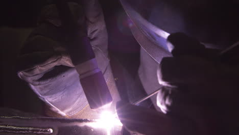 close up of welder wearing protective gloves working in factory