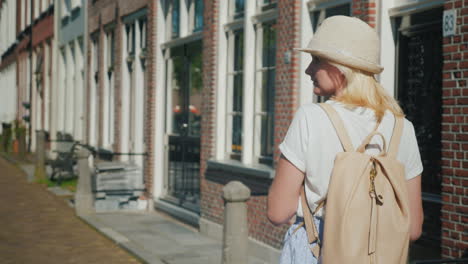 womanwith a backpack walks along narrow street