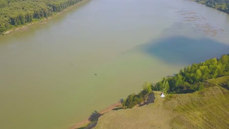 just-married-couple-on-steep-riverbank-on-sunny-day-aerial