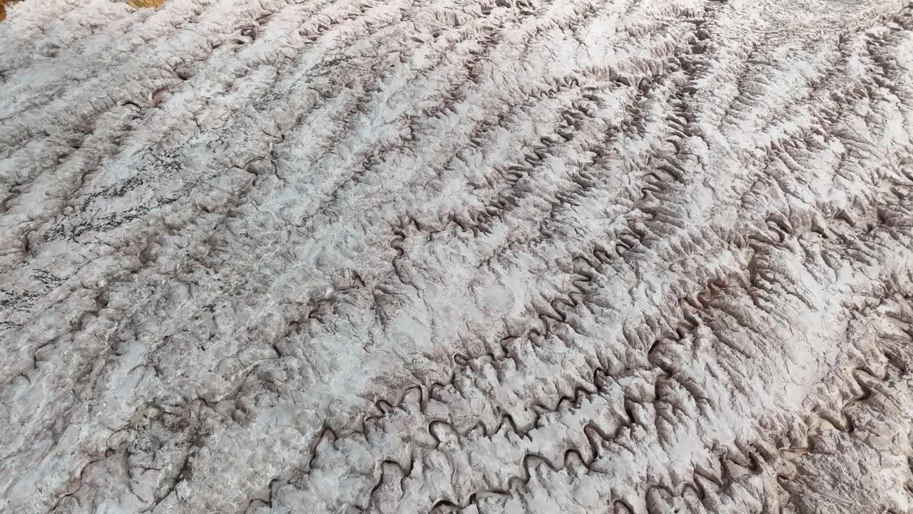 A detailed top-down aerial shot showcasing the intricate crystalline textures and rippled patterns of a massive salt glacier in the Congo, Africa
