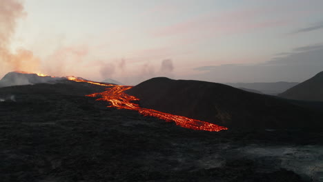 Fly-above-end-of-hot-lava-streams-flowing-from-active-volcano-crater.-Volcanic-landscape-at-dawn.-Fagradalsfjall-volcano.-Iceland,-2021