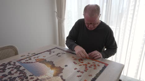 frustrated, angry, senior man tries to pound a puzzle piece in place