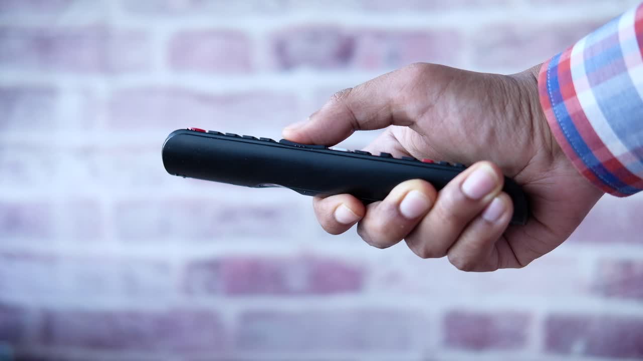 검은색 tv 리모컨을 들고 있는 사람