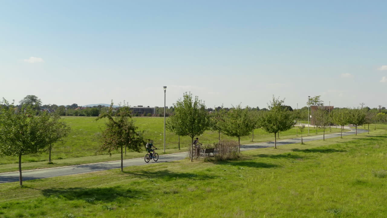 dos personas en bicicleta en el camino del callejón del árbol del campo en moravia, drone