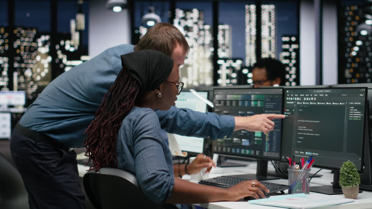 Software Developers Collaborating on Computer Code in Modern Office