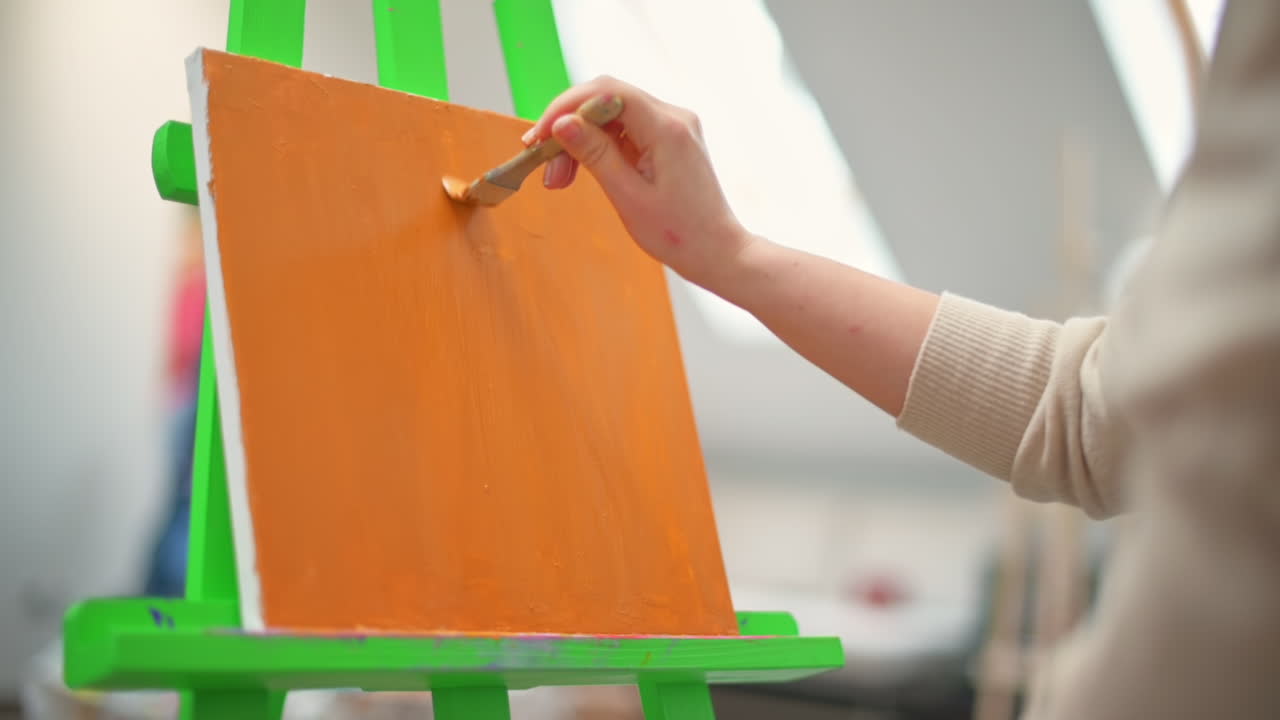 A woman painting a picture using a brush in a studio. Slow motion