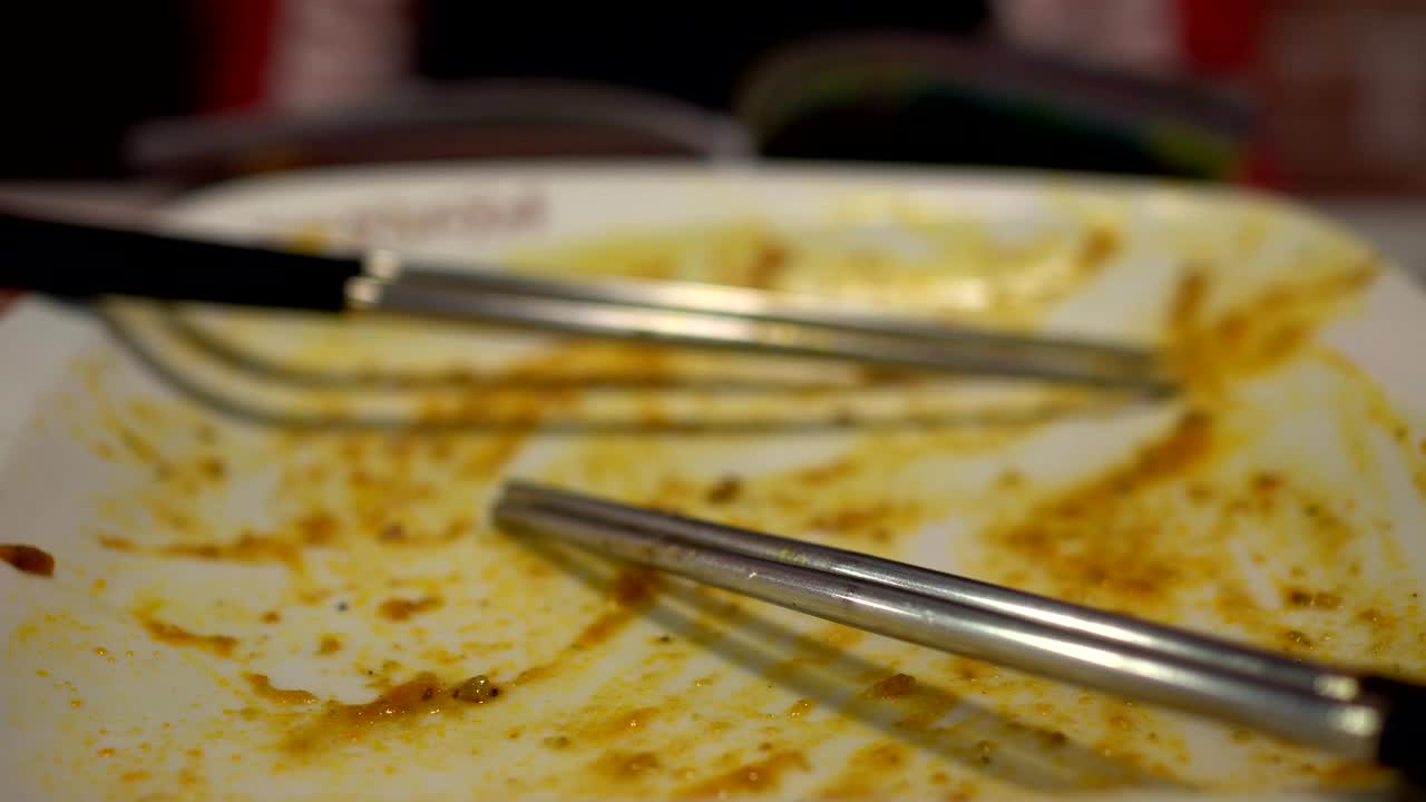 식당에서 음식을 먹은 후 빈 접시, 두 의 가락과 함께, 흐릿한 배경은 식사 후 책을 읽는 작은 소녀입니다.