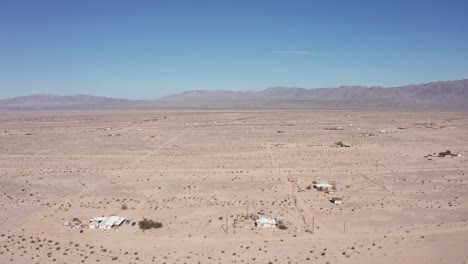 high and wide aerial shot of scattered homes in a barren and sparse californian desert