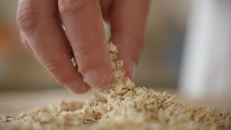 hand grabs oat flakes and drops in pile, slow motion close up with copy space