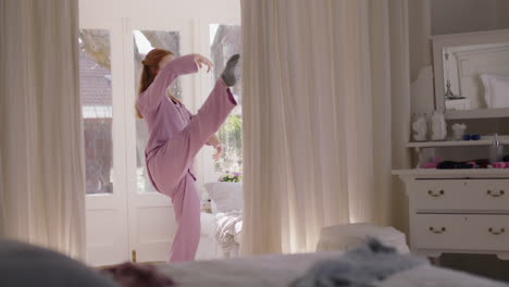 beautiful young woman practicing ballet dancing in bedroom rehearsing dance on weekend morning wearing pajamas