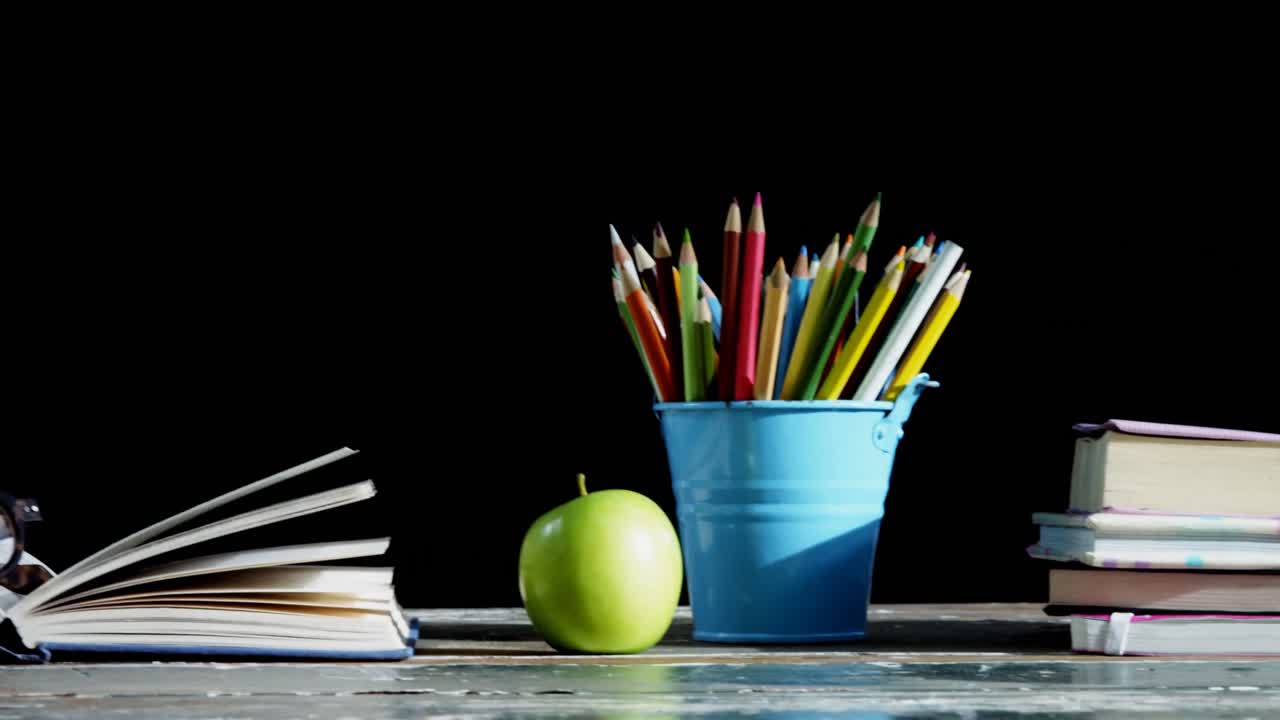 Green apple and school supplies on table