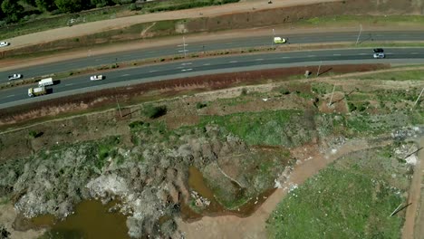 charco estancado de agua sucia en un vertedero que bordea la carretera africana con tráfico en kenia, áfrica