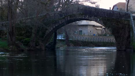vista estática del arco curvo en el puente romano triangular que cruza el río molgas