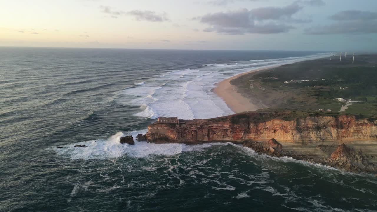 Splendida vista aerea della costa di Nazaré con scogliere imponenti e onde oceaniche.