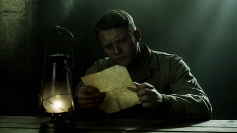 man reading a letter by lantern light