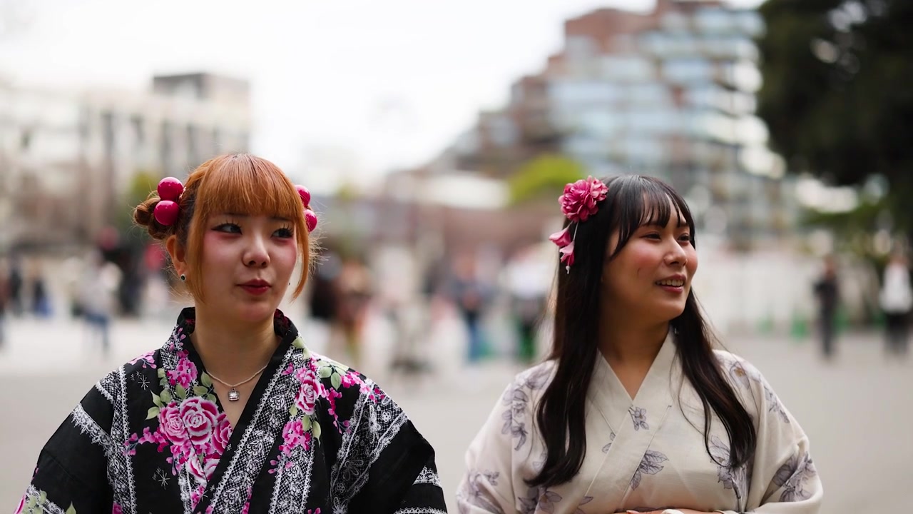 Çiçekli yukata giymiş genç Japon kadınlar, Tokyo'daki halka açık bir parkta yürüyor ve sohbet ediyor.
