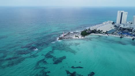 Luftaufnahme-Des-Leuchtturms-Von-Punta-Cancun,-Einem-Ikonischen-Bauwerk-In-Cancun,-Mexiko,-Der-Als-Wächter-Einen-Panoramablick-Auf-Das-Türkisfarbene-Wasser-Bietet,-Das-Sich-Bis-Zum-Horizont-Erstreckt