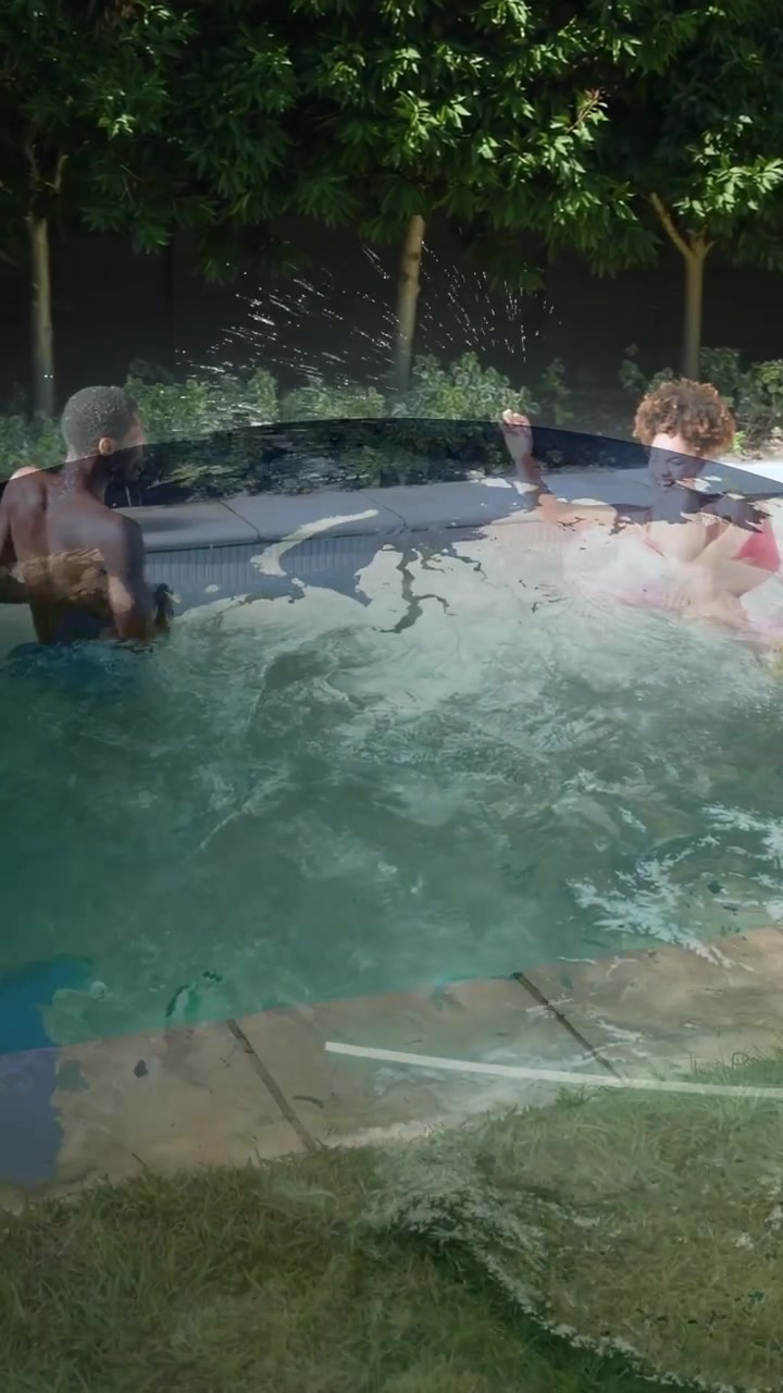 Video verticale: Due uomini che corrono verso il bordo piscina, si staccano e saltano, rinfrescandosi in un video di svago.