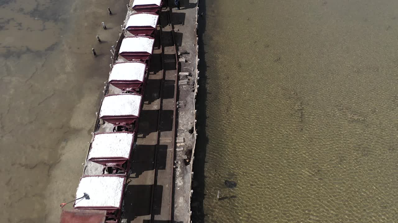 vuelo de dron de ángulo bajo sobre los rieles, descubriendo la maquinaria que mueve la sal al depósito