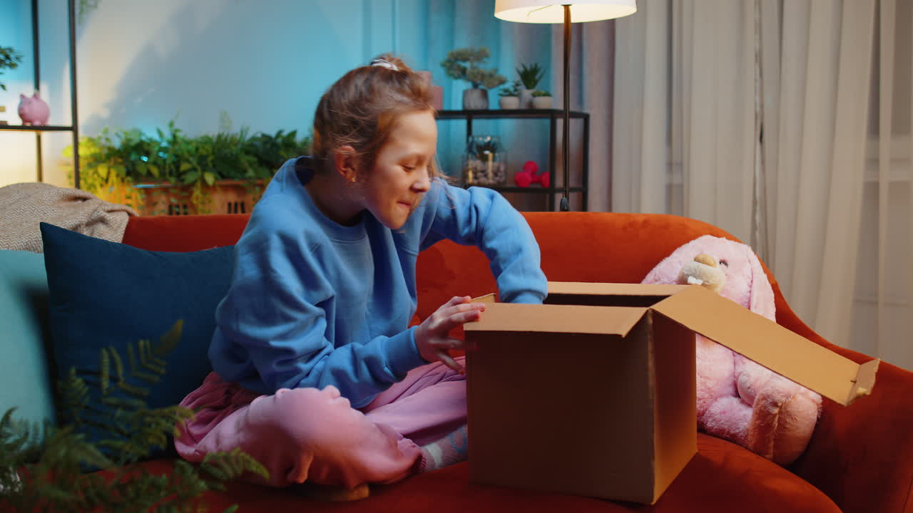 Little child girl shopper unpacking cardboard box delivery parcel online shopping purchase at home