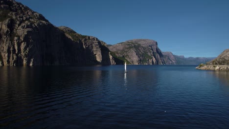 Drone footage of a sailing boat near Geiranger, surrounded by Nordic cliffs and clear blue water. Norway.